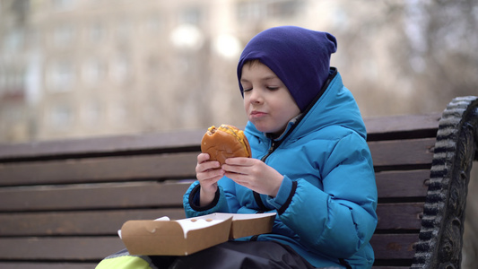 饿肚子的孩子在户外吃双层芝士汉堡视频