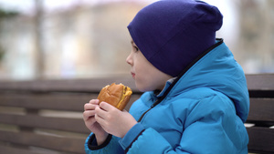 饿肚子的孩子在户外吃双层芝士汉堡21秒视频