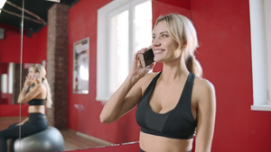 在健身俱乐部打手机的健身妇女16秒视频