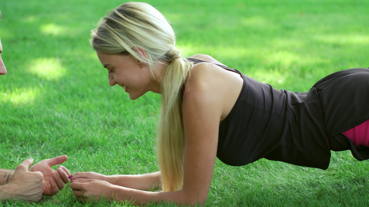 与躺在公园草地上的教练一起开展健身妇女培训木板练习视频