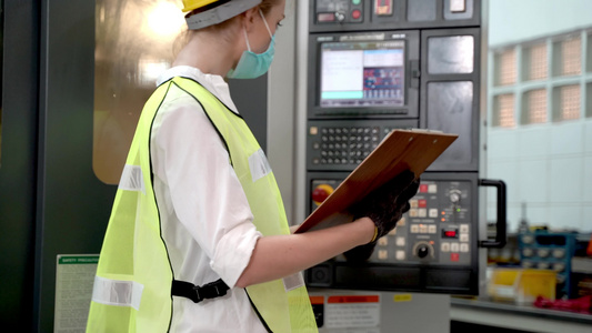 工厂职业经理妇女用报告纸检查面板重型机器并在机器周围走动。制造业的质量保证。概念工程师安全操作视频