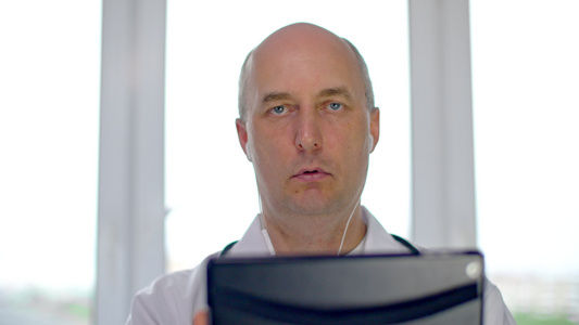 拥有数字平板电脑和在与病人进行时交谈的耳听器严重听力医生视频