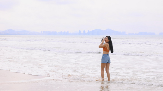 海边使用相机拍摄美好景象的美女视频