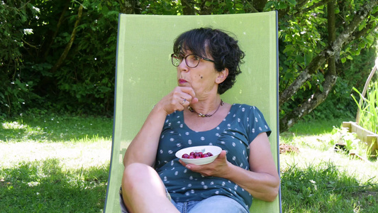 在花园吃樱桃的中年妇女视频
