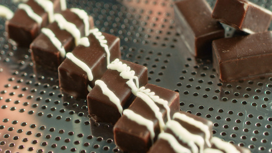 黑巧克力糖果上喷洒的熔化白玻璃视频