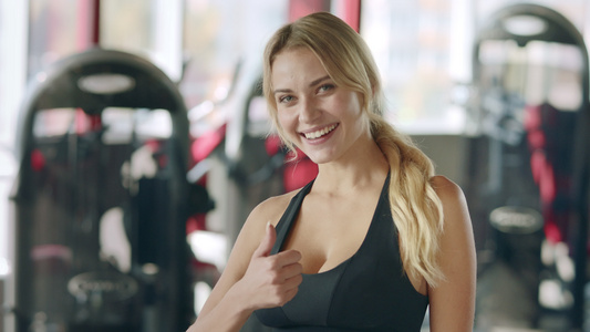 在健身俱乐部露出拇指手势的女性教练肖像视频