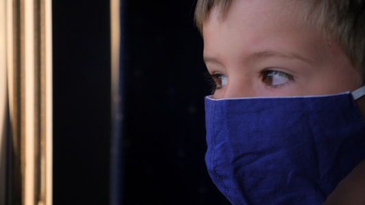一个戴着口罩的男孩望着火车窗外视频