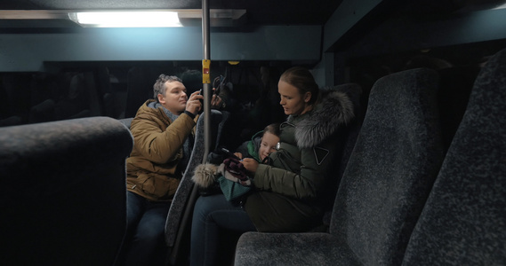妈妈和儿子在公共汽车上使用手机,父亲拍摄他们的视频视频