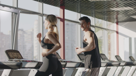 在健身中心操控运动机上的一对夫妇心操锻练视频