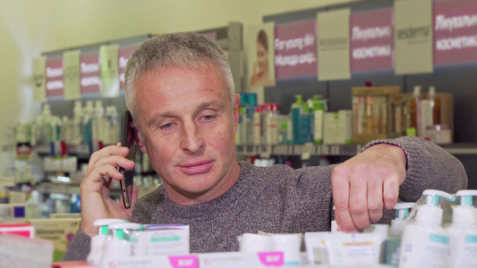 在药店买东西的时候高年男子在电话上聊天视频