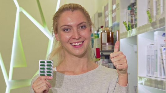 快乐健康的女人举起大拇指, 在药店拿着药水泡着药丸视频