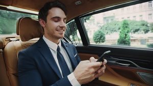 微笑着的商人做在商务车里使用智能手机上打字14秒视频