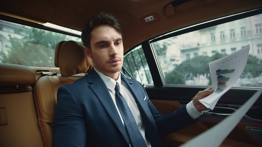 豪华轿车沙龙中专注的男性业阅读文件的肖像视频