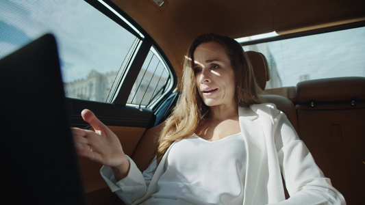 严格商业女性在现代汽车的笔记本电脑上提供视频聊天指导视频