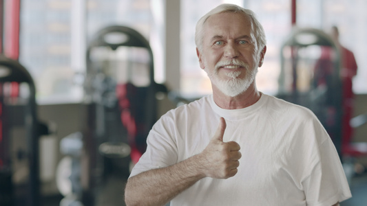 微笑的老人在健身俱乐部露出大拇指的手势视频
