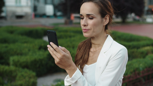 商务女性在城市散步时通过视频电话用智能手机发言视频