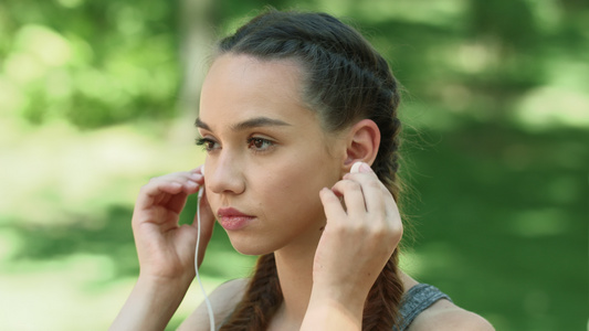 运动妇女在户外健身时用耳听器音乐视频