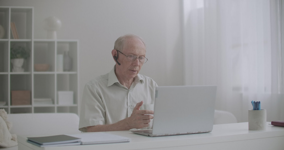 通过互联网进行电子学习,老年人在讲课,坐在膝上型电脑前坐在家里,在线交流视频