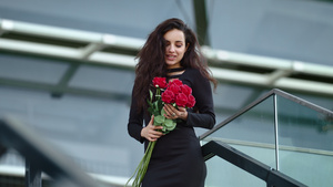 特写女人在街上手捧红色玫瑰闻花香幸福微笑30秒视频