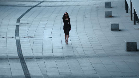 在街上摘太阳镜的穿着黑色连衣裙的优雅性感美女视频