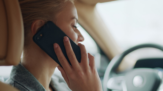 女性在汽车驾驶座上愉快地讲电话侧面特写视频