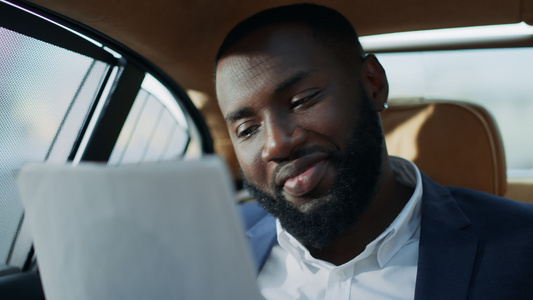 喜悦的非洲商务男士在汽车上阅读文件时微笑视频