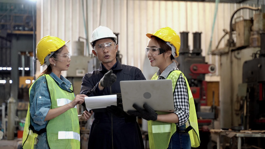 一群工厂男女工人用平板电脑和纸质文件报告会面和讨论，然后女工走路和说话。在工业工厂的背景下视频