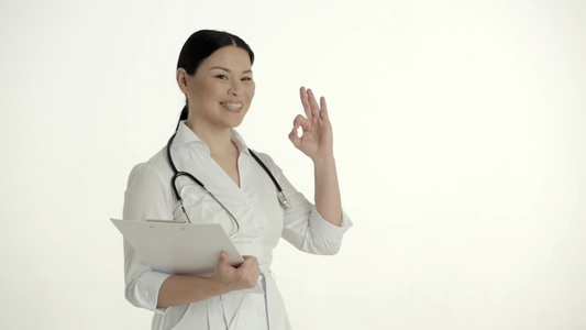 白背景的亚洲护士 微笑和举起拇指视频