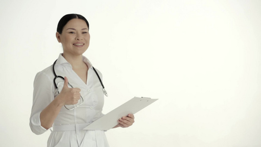 白背景的亚洲护士微笑和举起拇指视频