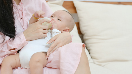 新生婴儿喝瓶装牛奶躺在他年轻母亲膝盖上视频