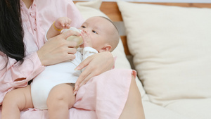新生婴儿喝瓶装牛奶躺在他年轻母亲膝盖上14秒视频