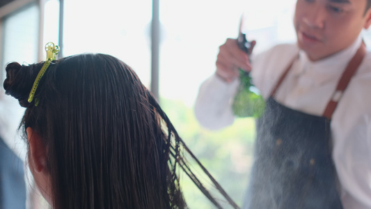 美容院理发师男子向女顾客长发喷洒头发液视频