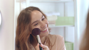 年轻妇女在浴室镜子上用化妆刷在脸施粉19秒视频