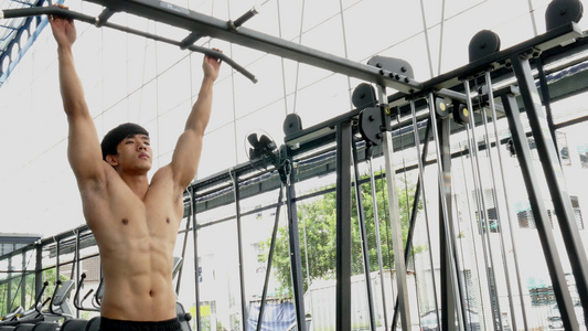 年轻的肌肉男在健身中心用机器进行锻炼。亚洲运动员在健身房训练。健美运动员男性在健身俱乐部锻炼。运动、健康的生活视频