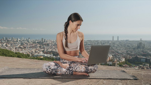 瑜伽女孩坐在垫子上用笔记本电脑15秒视频