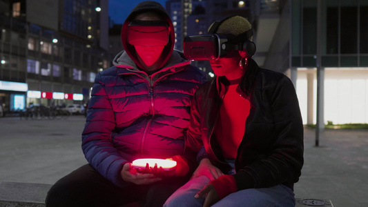 意大利城市夜间戴着 VR 护目镜和智能手机的男女视频