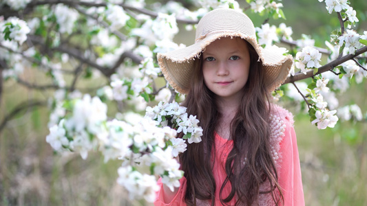 美丽的年轻女孩在苹果盛开的春天果园中行走视频