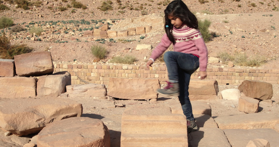 约旦佩特拉沙漠景观中在石头上行走的女孩视频