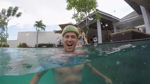 一个穿着西瓜头盔的年轻人在派对游泳池里玩得开心19秒视频