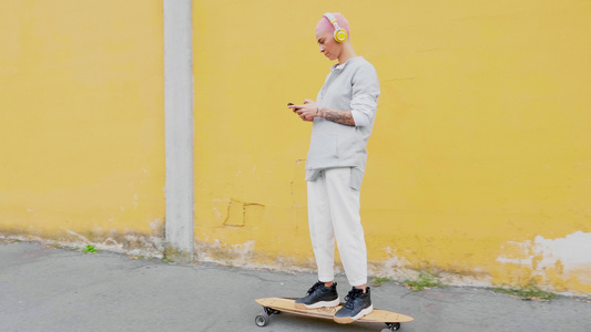 意大利年轻女子长板滑冰和用智能手机听音乐视频