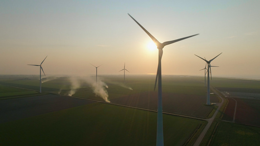 日落时田野中的风力涡轮机和烟雾视频