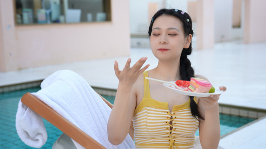泳池边躺椅上吃甜点的女生视频