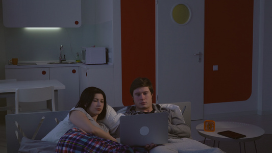 女人和男人躺在床上观看录像视频