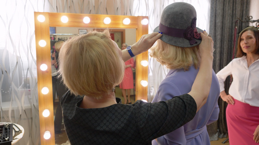 优雅的女人在时尚精品前镜中选择时尚的帽视频