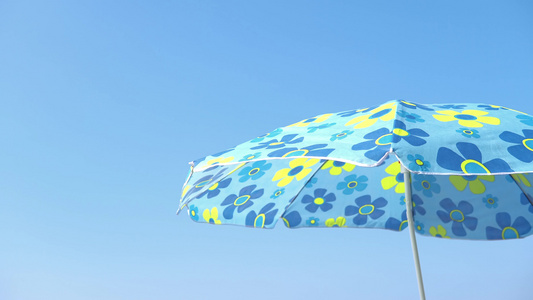 雨伞在沙滩上轻微的微风向蓝天移动视频