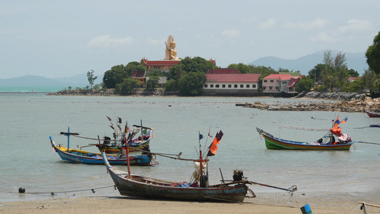 泰国苏梅天堂热带异国情调的岛屿海边，被平静的水和古老的穆斯林钓鱼长尾船包围的大佛寺。文化和宗教和平共处视频