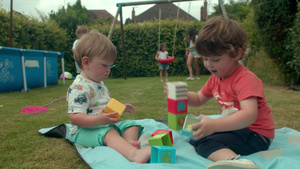两个男孩坐在花园里的毯子上玩积木19秒视频