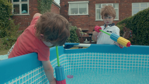 两个小男孩在花园的戏水池里玩水枪8秒视频