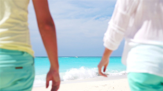 年轻夫妇在热带海滩握手,闭合慢动作视频