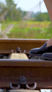 穿着裙子漫步在铁轨上的女孩脚步特写实拍走在铁轨上视频
